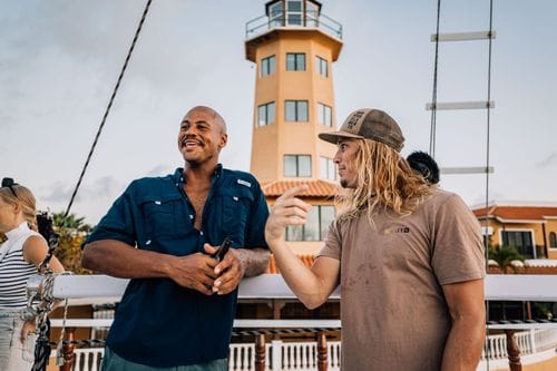 Two crew members talking on deck beside the marina lighthouse