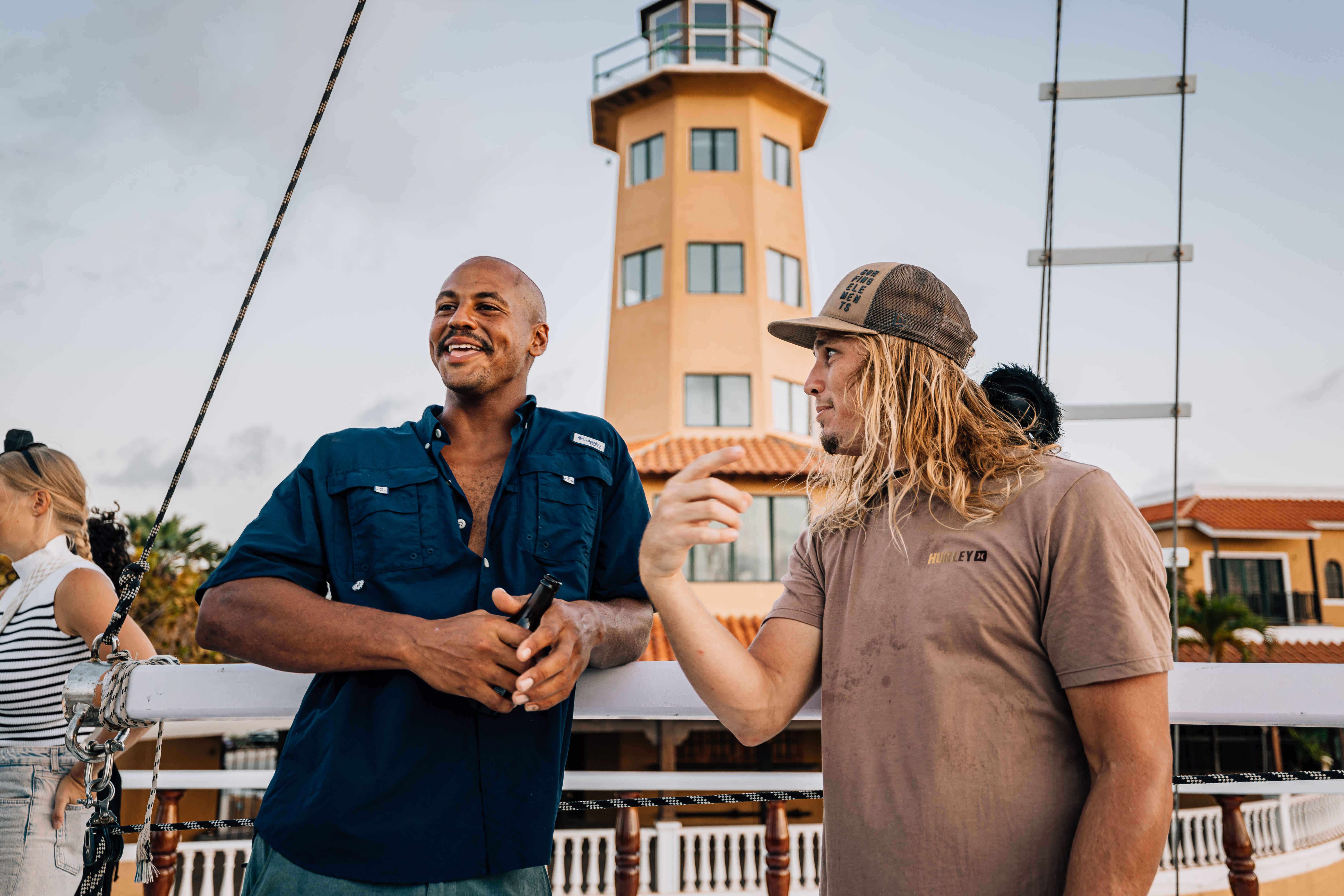 Two crew members talking on deck beside the marina lighthouse