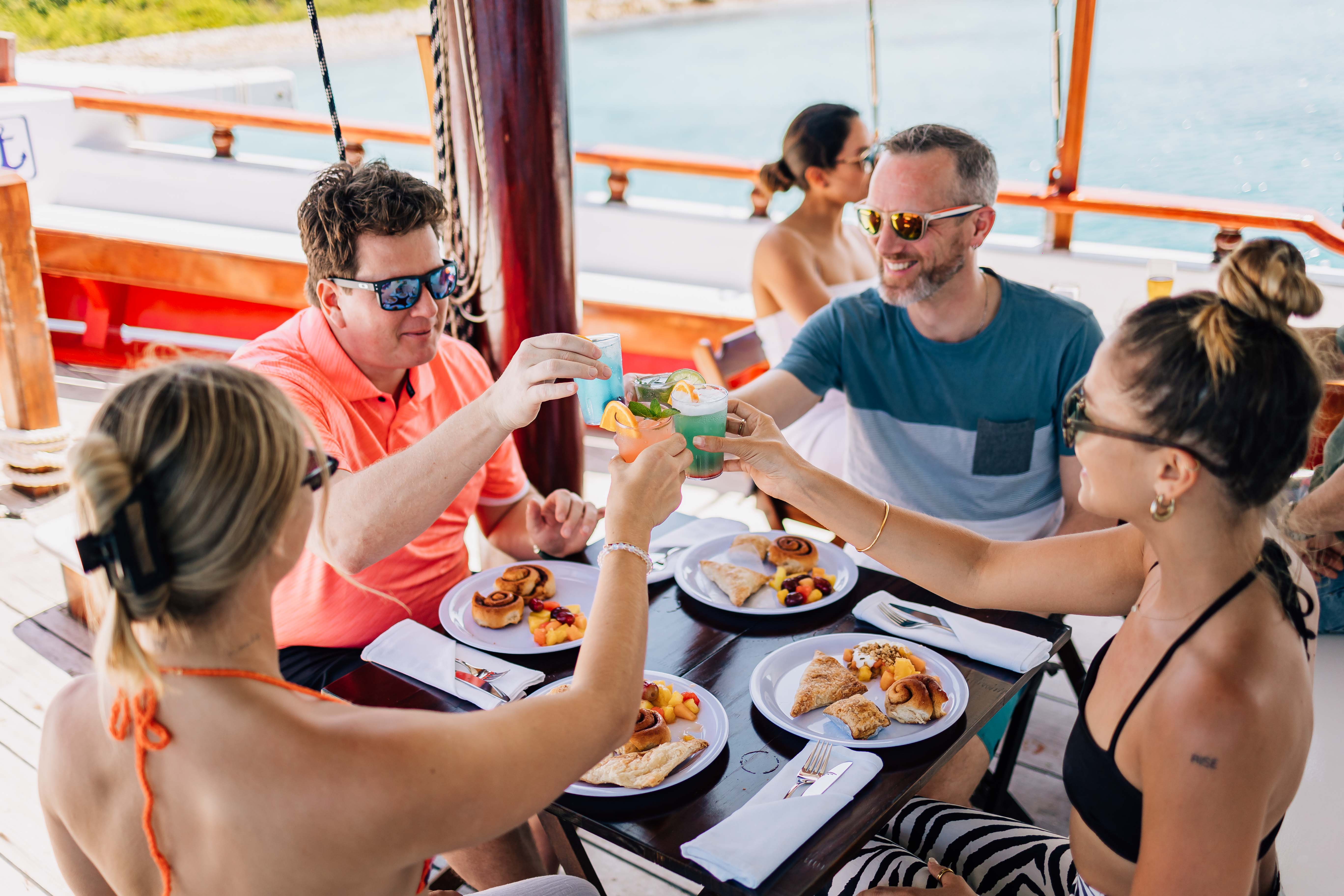 Guests raising a toast over cocktails and small plates on deck
